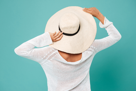 Back view photo of pretty young lady wearing hat posing over blue background.の写真素材