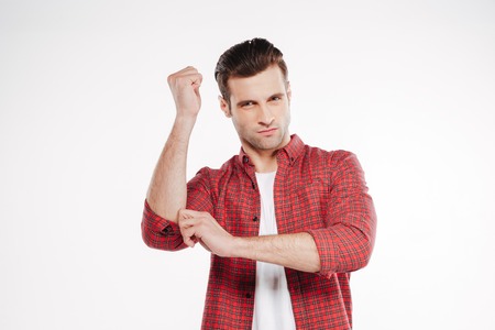 Serious man in shirt which posing in studio with invisible Nunchuck and looking at camera. Isolated...