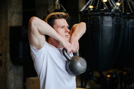Side view of Athletic man which doing exercise with weight in gym