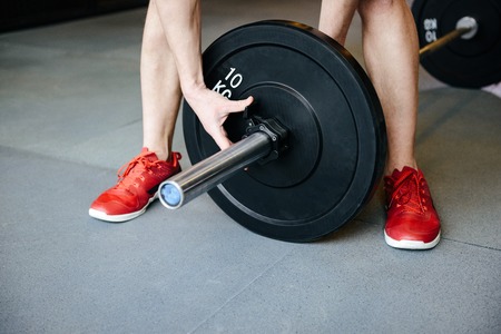 Cropped image of man which collects the barbell in gymの写真素材