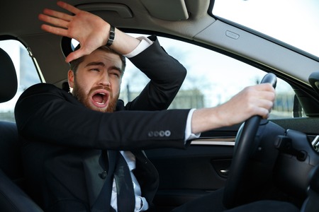 Portrait of a screaming businessman nearly crashing car during his tripの写真素材