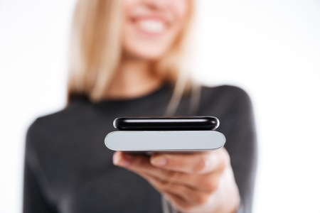 Cropped image of smartphone and power bank in hand of woman on background. Focus on gadgets. Isolated white backgroundの写真素材