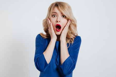 Picture of shocked young lady dressed in blue dress posing over white background.の写真素材