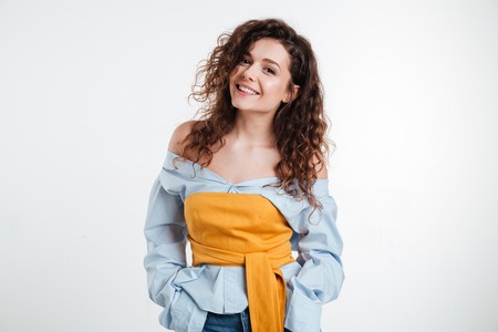 Beautiful young woman standing with hands in pockets isolated on a white backgroundの写真素材