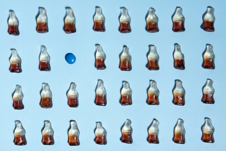 Top view picture of a lot of sweeties chewing candy in bottle form over blue table background.