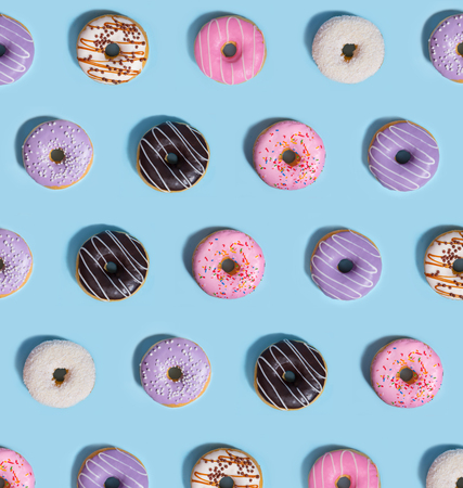 Picture of a lot of colorful sweeties donuts over blue table background.の写真素材