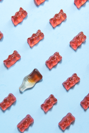 Image of a lot of sweeties chewing candy in teddy bear and bottle form over blue table background.の写真素材