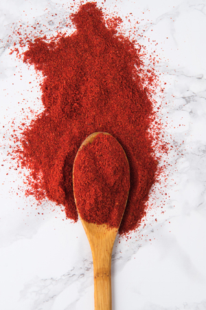 Top view of a wooden spoon with paprika powder on white marble backgroundの写真素材