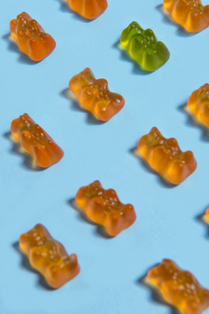Image of a lot of sweeties chewing candy in teddy bear form over blue table background.の写真素材