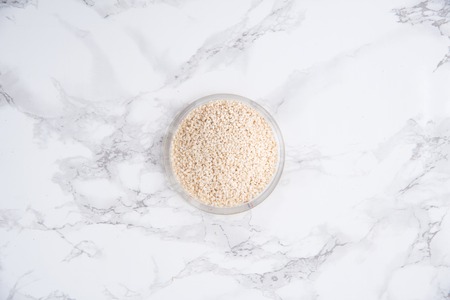 Top view of white sesame in a bowl isolated on white marble tableの写真素材