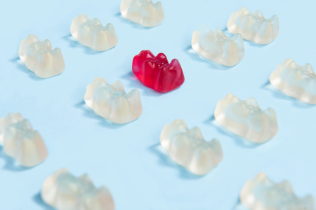 Image of a lot of sweeties chewing candy in teddy bear form over blue table background.の写真素材