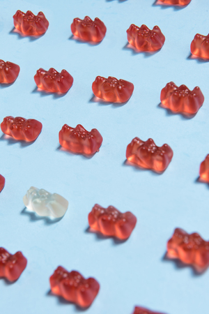 Image of a lot of sweeties chewing candy in teddy bear form over blue table background.の写真素材