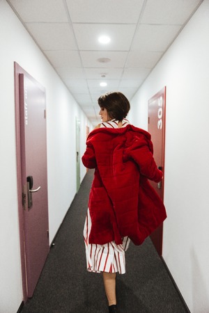 Back view of attractive young woman in red coat running in corridorの写真素材