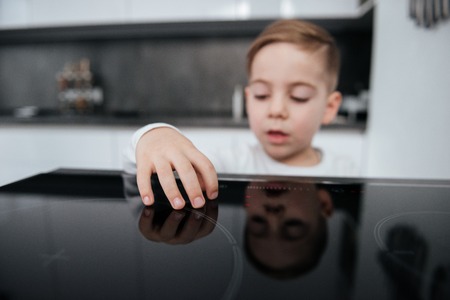 Picture of dangerous situation in the kitchen. Child playing with electric oven.の写真素材