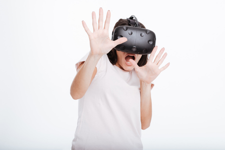 Photo of shocked scared lady wearing virtual reality device over white background.の写真素材