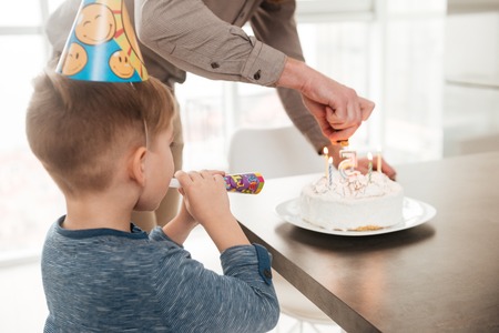 Back view of young father with the birthday cake of his little son.