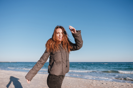 Happy Woman dressed in warm jacket on date on beach near the sea. Side viewの写真素材