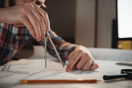 Close up portrait of a man hands using compass to draw a graph while sitting in the officeの写真素材