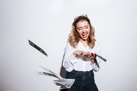 Happy excited woman throwing money over white backgroundの写真素材