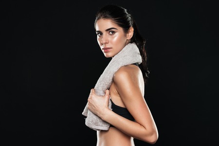 Image of sports lady in gym standing over black background and holding towel.の写真素材