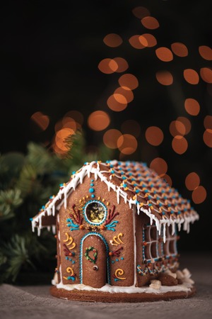 Christmas traditional gingerbread house decorated with colorful glaze over shining backgroundの写真素材