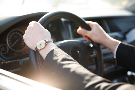 Cropped image of business man in suit driving carの写真素材