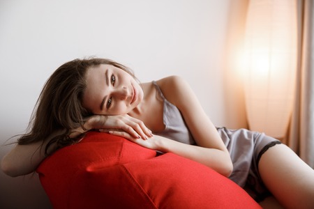 Pretty Woman in nightie which lying on the bag chair and looking awayの写真素材