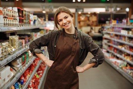 Picture of young happy woman in supermarket choosing products. Looking at camera.の写真素材
