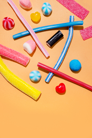 Mixed colorful candies jellies on the pink background with copyspace in the middleの写真素材