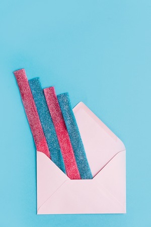 Top view of jelly sugar stripes sticking out from an envelope isolated on blue backgroundの写真素材