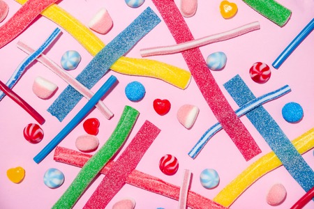 Mixed colorful candies jellies isolated on pink backgroundの写真素材