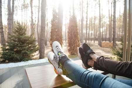Close-up shot of legs of couple that sitting near table and forestの写真素材