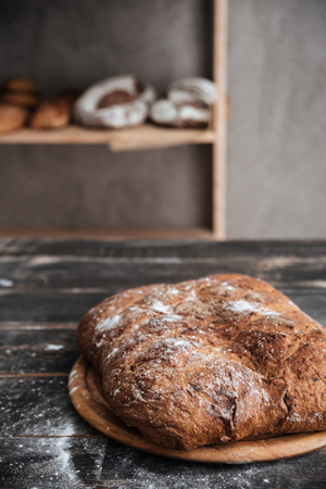 Photo of bread with flour on dark wooden table at bakeryの写真素材