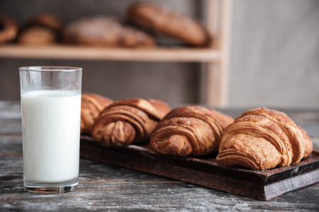 Image of croissants on dark wooden table with milk at bakeryの写真素材