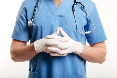 Close up of a male medical doctor or nurse wearing surgical gloves and stethoscope isolated on white backgroundの写真素材