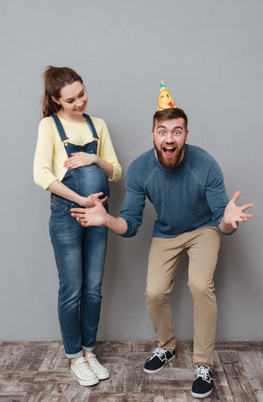 Portrait of a happy young family celebrating future child birth isolated over gray backgroundの写真素材