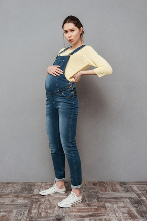 Photo of tired pregnant woman posing isolated over grey wall. Looking aside.の写真素材