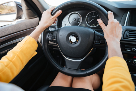 Close up of female hands holding car wheel and drivingの写真素材