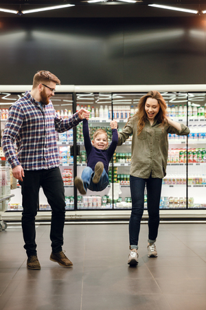 Vertical image of a  family walking and playing in supermarket. Full length portraitの写真素材