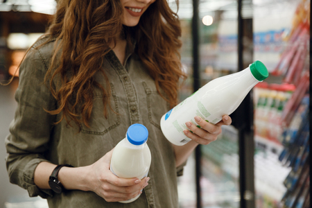 Cropped image of a woman in green shirt choosing a milk in supermarketの写真素材