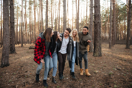 Image of smiling group of friends walking outdoors in the forest. Looking aside.の写真素材