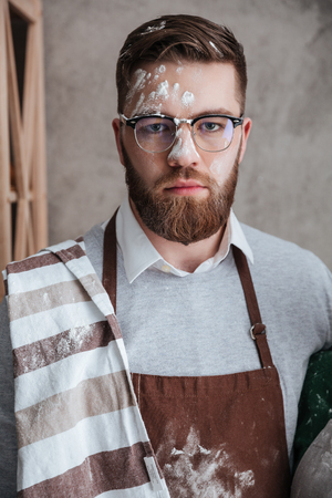 Portrait of bearded man in glasses and apron whose face stained with flourの写真素材