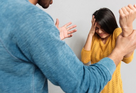 Agressive man beating up his wife and holding strongly her hand isolated