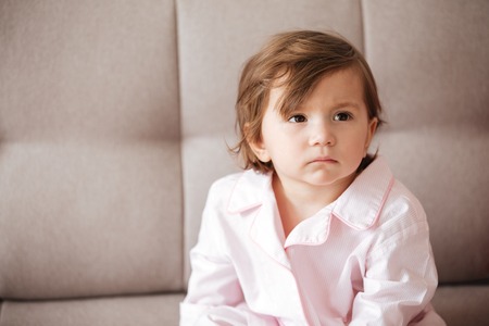 Upset child sitting on sofa and looking awayの写真素材