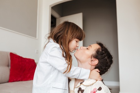 Cute little girl hugging and kissing her motherの写真素材