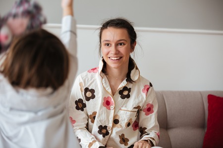 Back view of playing child against smiling mother in living roomの写真素材