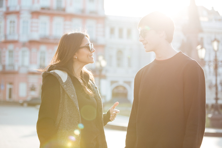 Image of happy young lady walking outdoors with her brother. Looking aside.の写真素材
