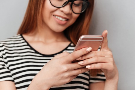 Close up of smartphone in hands of young asian woman isolatedの写真素材