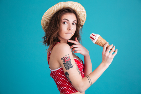 Photo of amazing young woman with ice-cream looking at camera isolated over blue background.の写真素材