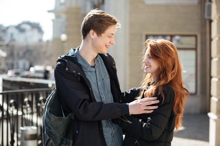 Cheerful couple of young cute students hugging in the streetの写真素材